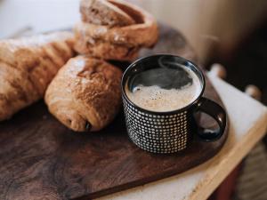 a cup of coffee on a wooden board with bread at The Green One On The End in Thurton