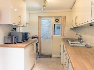 eine Küche mit weißen Schränken und einer Mikrowelle in der Unterkunft Steps End in Brixham