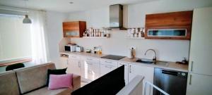 a kitchen with white cabinets and a sink and a couch at Apartmán Slunečná in Moravská Třebová