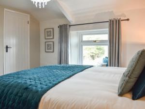 a bedroom with a large bed with a window at Heather Cottage in Bishop Auckland