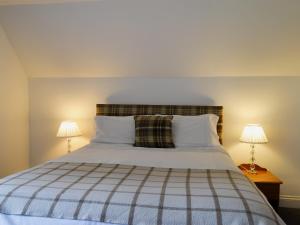 ein Schlafzimmer mit einem großen Bett mit zwei Lampen in der Unterkunft Checkers Cottage - Beaufort Estate in Belladrum