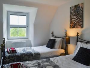 ein Schlafzimmer mit zwei Betten und einem Fenster in der Unterkunft Checkers Cottage - Beaufort Estate in Belladrum