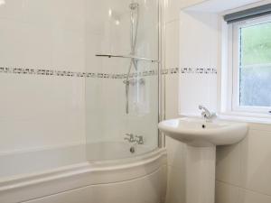 ein weißes Badezimmer mit einem Waschbecken, einer Badewanne und einer Dusche in der Unterkunft Checkers Cottage - Beaufort Estate in Belladrum