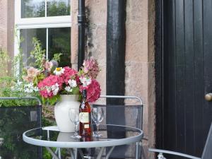 einen Tisch mit einer Flasche Wein und Blumen darauf in der Unterkunft Checkers Cottage - Beaufort Estate in Belladrum + 28 Fotos