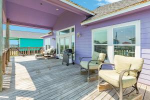 a purple house with chairs and a grill on a deck at Purple Paradise Beachy Fun Bay Beach Views in Hercules Offshore Heliport +29 photos