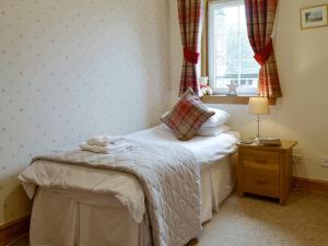 a small bedroom with a bed and a window at Baldowrie Farm Cottage in Ardler +3 photos