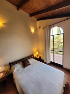 a bedroom with a bed and a large window at Cabañas El Paso in Villa del Dique
