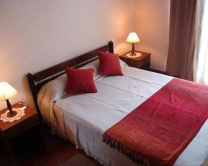 a bedroom with a bed with red pillows on it at Cabañas El Paso in Villa del Dique +59 photos