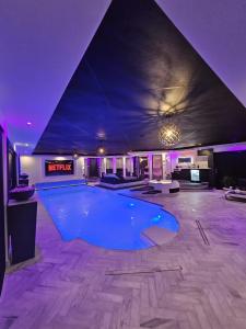 a large swimming pool in a room with purple lighting at Bed & Wellness Malina deluxe in Lelystad