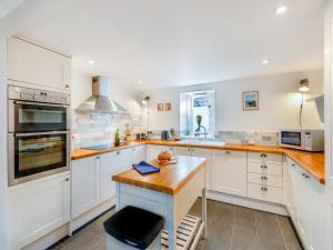 Una cocina con gabinetes blancos y una encimera de madera. en The Granary - Uk48740, en Gaerwen