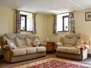 two chairs and a couch in a living room at Bucknole Farm - The Old Shippon in Northleigh