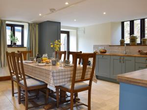 a kitchen with a table and chairs in a kitchen at Bucknole Farm - The Old Shippon in Northleigh