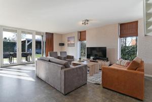a living room with couches and a flat screen tv at Villa Mastlo 2x 10 persons Ouddorp large garden, 1500 meters to the dunes and beach with 2 jacuzzi's - not for companies in Ouddorp