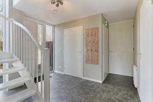 a hallway with a staircase in a home with white walls at Villa Mastlo 2x 10 persons Ouddorp large garden, 1500 meters to the dunes and beach with 2 jacuzzi's - not for companies in Ouddorp
