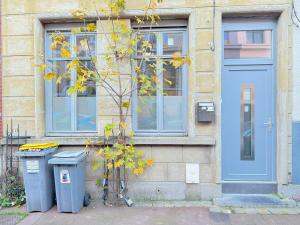 a building with a blue door and two trash cans at Les arts chambres 4 SDB privatif 1 er etage in Roubaix