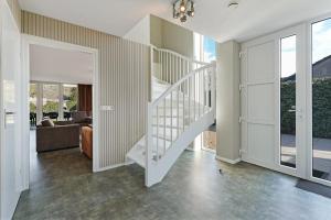 een witte trap in een woonkamer met glazen schuifdeuren bij Villa Mastlo 2x 10 persons Ouddorp large garden, 1500 meters to the dunes and beach with 2 jacuzzi's - not for companies in Ouddorp