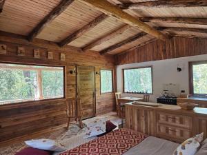 a room with a bed and a desk and two windows at Cabaña Refugio Cascada in Llanada Grande