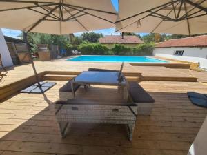 a patio with two umbrellas and a swimming pool at Villa don du ciel in Soustons