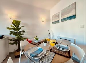 a dining room with a wooden table with plates and wine glasses at Superbe T2 vue mer avec ascenseur 22 in Canet-en-Roussillon
