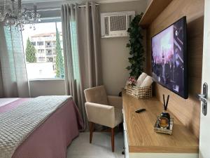 a bedroom with a bed and a desk with a tv at Refúgio Sofisticado no Centro de Nova Friburgo in Nova Friburgo