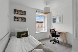 a bedroom with a bed and a desk and a window at Holyrood Duplex 3-Bedroom Apartment in Edinburgh