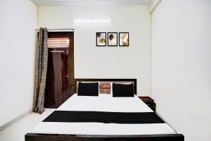 a bedroom with a white bed with black and white sheets at Hotel O Parth Hotel And Restaurant in Fīrozābād