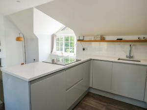 a kitchen with white cabinets and a sink and a window at The Gatekeepers Cottage - Skerry Vore in Llandudno Junction +25 photos