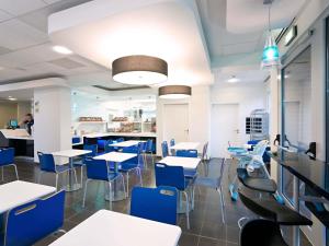 Un comedor con mesas y sillas azules. en ibis budget Torun, en Toruń