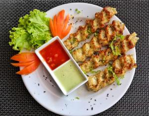 a plate of food with chicken skewers and lettuce and sauce at Twin Sands Resort Penthouse in Patong Beach