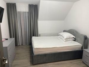 a small bedroom with a bed with white sheets at Vila Cantacuzino in Buşteni