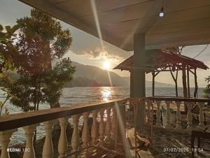 a view of the ocean from a porch with the sunset at Alexander Homestay in Tuktuk Siadong