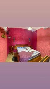 a bedroom with pink walls and a large bed at Suites Recanto da Sarah in Flecheiras