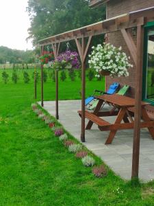 un tavolo da picnic e una panca sotto un pergolato con fiori di Domek letniskowy Słoneczny Zakątek a Frombork Altre 8 foto