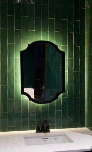 a bathroom sink with a mirror on a green tiled wall at HIDE&SEEK Homestay in Ấp Tân An (1)
