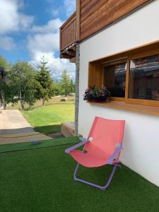 ein rosa Stuhl, der auf dem Gras neben einem Haus steht in der Unterkunft La Suite Du Skilodge in La Toussuire