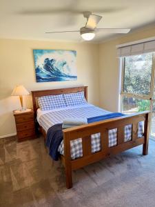 1 dormitorio con cama de madera y ventana en Casablanca Beach House, en Torquay