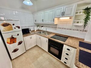 Una cocina con gabinetes blancos y un refrigerador blanco. en Casa Ñaña Pay, en La Mareta