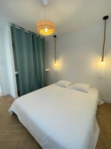 a bedroom with a large white bed with two pillows at L'Escale - Charming Seaside house by Harbor in Cancale