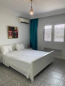 a bedroom with a large white bed with a blue curtain at Marina Duplex View & Style in Monastir