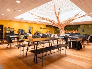 ein Restaurant mit Tischen, Stühlen und einem Baum in der Unterkunft ibis Styles Calais Centre in Calais
