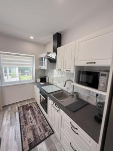 a kitchen with white cabinets and a sink and a window at Varázsvilág Vendégház in Olaszfalu +8 photos
