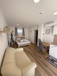 a living room with a white couch and a desk at Varázsvilág Vendégház in Olaszfalu