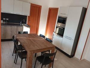 une cuisine avec une table en bois et des chaises noires dans l'établissement Casa Letizia, à Bernalda 4 autres photos