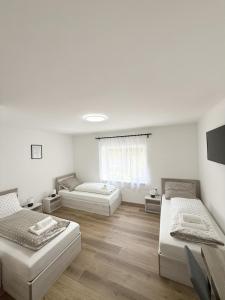 a white room with three beds and a window at Varázsvilág Vendégház in Olaszfalu