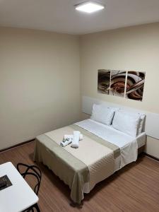 a hotel room with a bed with white sheets at Hotel Avenida in Nova Friburgo +128 photos
