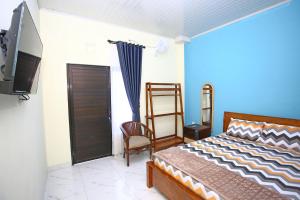 a bedroom with a bed and a tv and a chair at Mentari Homestay in Sentool +5 photos