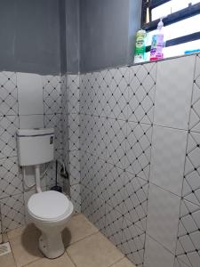 a bathroom with a toilet in a white tiled wall at LV Homes in Ongata Rongai 