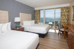 a hotel room with two beds and a desk at Ocean Breeze Inn Vero Beach in Vero Beach +20 photos