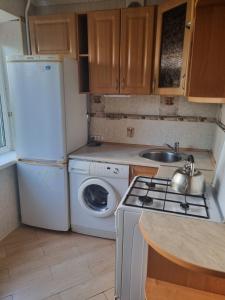 a small kitchen with a refrigerator and a washing machine at Затишна 1 кімнатна квартира біля метро Дарниця in Kyiv