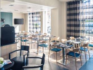 a restaurant with tables and chairs and a tv at Hôtel Mercure Thionville Centre Porte du Luxembourg in Thionville